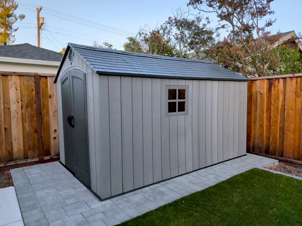 Gray backyard storage shed assembled on a paved base